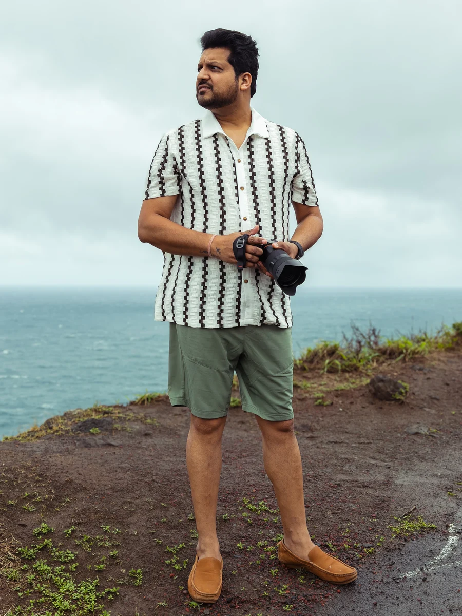 Azar Jindal holding his camera beside the ocean