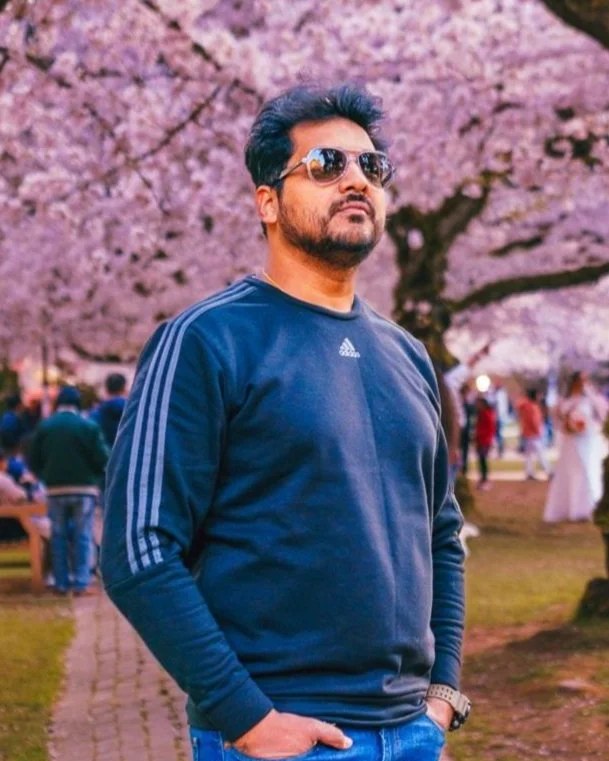 Azar Jindal standing under the cherry blossoms at the University of Washington Quad
